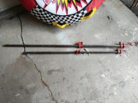 Two metal pipe clamps laid out on concrete floor, one longer than the other, showing full length and clamp mechanisms