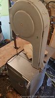 Front perspective of cast iron bandsaw showing frame, base cabinet and steel table