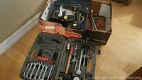 Box containing assorted tools including 18V Mastercraft cordless drill with batteries, wrenches, screwdrivers, and clamps.
