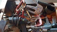 Box of assorted tools including clamps, drill, hand saw, and small hammer