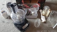 Overall view of the KitchenAid food processor with accessories spread out, showing base, bowl, white handheld attachment, and clear popcorn maker container.