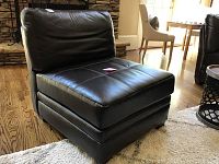Front angle view of the dark brown faux leather armless chair showing cushioned seat and backrest with stitched detail.