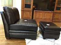 Side view of armless chair and ottoman placed on area rug in living room.