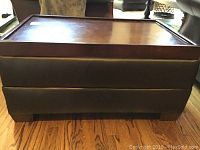 Side view of the rectangular table showing faux leather sides and wooden base on wooden floor