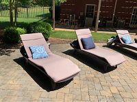 Two chaise lounges side by side on pool deck with cushions and throw pillows visible