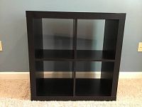 Front view of black 4-cube open back bookcase showing four square compartments.