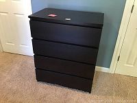Front view of black 4-drawer chest showing smooth front and inset drawer pull grooves.