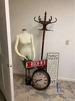 Full lot showing coat rack, mannequin, 'Rock-N-Roll' sign, clock, 'Family Rules' sign, and some artificial plants