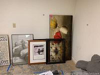 Wide shot showing all framed items leaning against a wall on floor of a room.