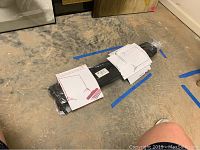 Photo of folded backdrop stand system inside carrying bag lying on floor with instruction sheet visible