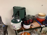 Wide shot of the assortment including Crockpots, travel case, bowls, food scale, fryer, and pumpkins.