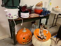 Wooden sofa table with various items on top and large Halloween pumpkin decoration below.