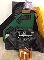 Multiple game items stacked including two folding table tops, black carrying bags, wooden chip holder with chips, and dice