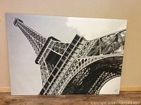 Front view of large black and white Eiffel Tower photo printed on canvas, showing detailed iron structure and cloudy sky background.