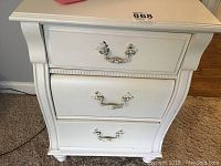 Front view of white Stanley nightstand showing three drawers and ornate handles