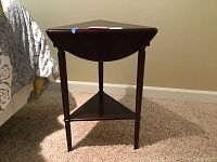 Front view of the wooden nightstand showing the curved front drawer and lower triangular shelf