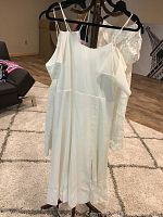 Photo of six white dresses hanging on a rack in a room showing different styles including sleeveless and lace.