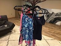 Several colorful ladies shirts on hangers showing various patterns and styles like sleeveless, off-the-shoulder in blue, black, pink tones.