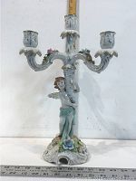 Front view of the porcelain candle-holder showing the cherub figure and three candle arms with floral decoration.