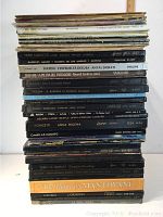 Stack of approximately 30 vinyl records showing spine labels with composer names and titles, mostly classical and opera music