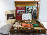 Wide view of wooden box open, displaying art books, sign reading Art Notes Oil Painting, and painting tools inside compartments.