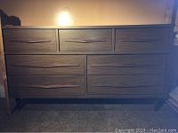 Front view of the vintage Mid Century Modern sideboard with seven drawers and wooden handles.