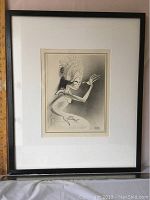 Framed lithograph showing the entire artwork with white matte and black frame, depicting a figure in profile wearing a headdress.