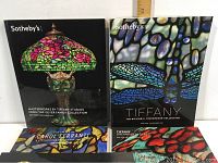 Five Sotheby's Tiffany auction catalogues displayed showing colorful Tiffany stained glass lamps and decorative glass on the covers.