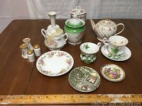 View of complete lot showing varied tea cups, bowls, plates, a teapot, vase, and salt and pepper shakers.