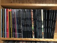 Photo showing a row of Canadian art auction catalogues on a wooden shelf, majority with black spines and white text, mostly titled by Jonker Fine Art Inc. or Jonker Waddington's.