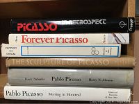 View of six Picasso art books stacked on a shelf, showing titles and thickness of each book.