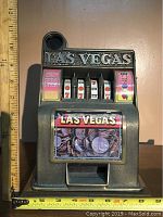 Front and top view of the vintage Las Vegas coin-operated slot machine with coins graphic on the front and slot reels visible.