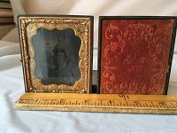 Front view of antique couple photo framed in black case with gold ornate trim, showing detached hinge.