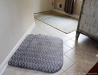 View of 2 gray kitchen rugs with white oval pattern and blue Kaleen rug in foyer