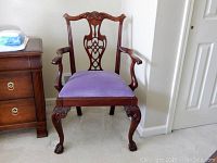 Front view of antique Chippendale style armchair with lilac velvet seat and wooden carved clawed cabriole feet.
