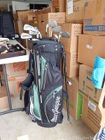 MacGregor golf bag with 9 golf clubs in storage area with cardboard boxes