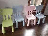 Four plastic kids chairs arranged in a row, showing colors and condition