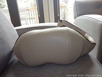 Side view of beige back massager belt showing contoured shape and smooth surface.