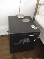 Front and top angled view of the black Sentry safe, showing top surface and combination lock door front.