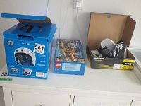 Overview of the blue box containing Bauer helmet, Lego set box, and open Bauer Supreme S140 youth skates box with skates inside.