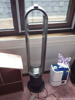 Front view of bladeless fan next to small wooden shelf and humidifier