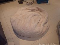 Soft plush bean bag chair in off-white on tiled floor.