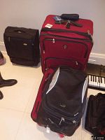 Photo of 3 red Swiss Gear suitcases of different sizes and the black Nike wheeled knapsack showing exterior condition and size