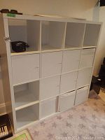 Full view of the white IKEA shelving unit with cupboards and fabric bins installed. Shows general condition.