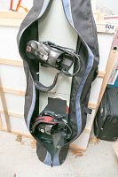 Snowboard with bound bindings inside a Flow brand carrying bag, showing the snowboard and bindings details.