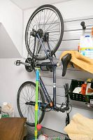 Side view of entire bike hanging on wall rack, shows frame, wheels, pedals and coiled cable lock.