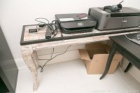 Full view of the wood sofa table showing the distressed finish, black edges, curved legs, and some electronic items on top.