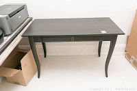 Front angled view of the dark stained wood IKEA table showing the overall shape and drawer front.