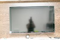 Front view of TV mounted on wood wall with remote control and power module below