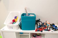 Wide view of the toys including various colorful pieces inside bins and scattered on the surface showing multiple toy types